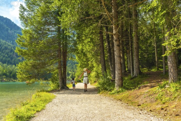 Tourists enjoying the stunning landscape of the dolomites while walking on a gravel path by the