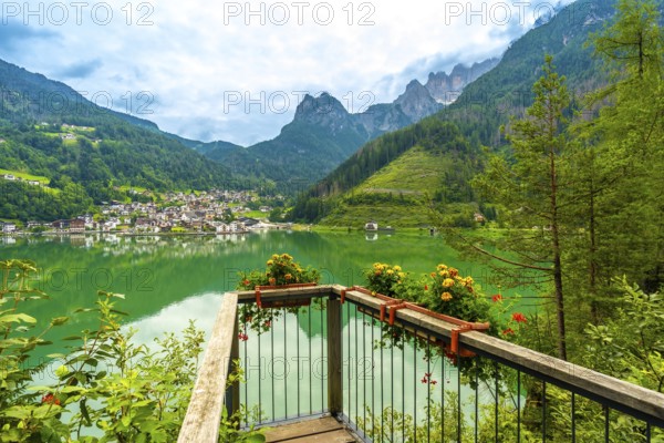 Wooden viewpoint overlooking the picturesque village of alleghe, reflecting on emerald waters