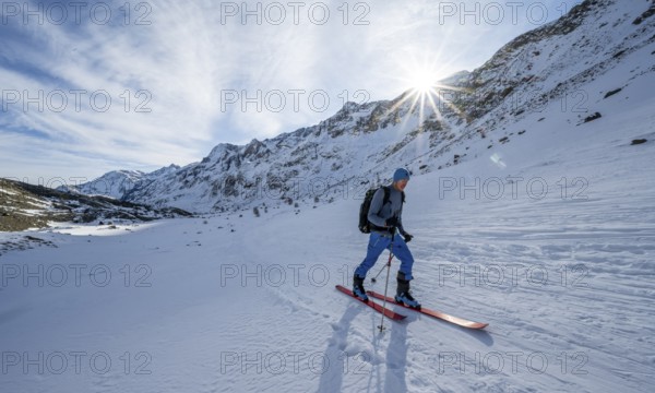 Ski tourers in the rear Martell Valley, snow-covered mountain landscape with sun star, Ortler Alps,