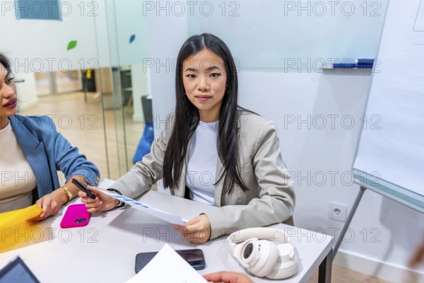 Young asian businesswoman leading a meeting with colleagues in a modern coworking office,