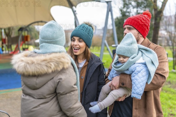 Parents and children enjoying playful moments together in winter attire at the playground, sharing