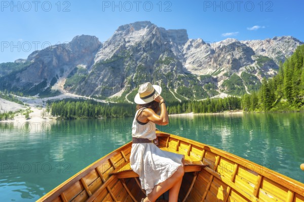 Young woman wearing a straw hat enjoying a boat trip on the turquoise waters of lake braies with