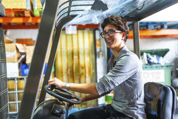 Side view of a happy caucasian woman with short hair and eyeglasses driving forklift in a