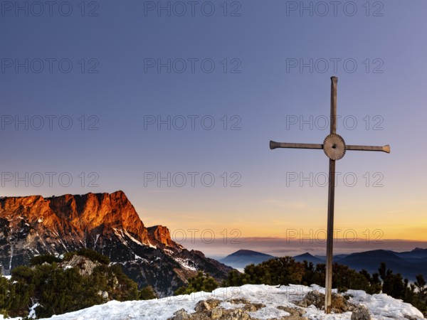 Sunrise at the summit cross of the Rauhen Kopf, behind the Untersberg, Berchtesgaden Alps,