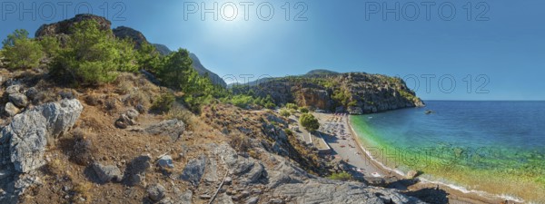 Expansive Ahata Beach panorama with beach, mountain backdrop and bright sunlight over the sea,
