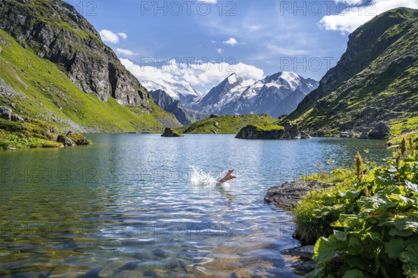 Woman taking a dip, cooling off in the mountain lake Lac de Louvie, behind the summit of the Grand