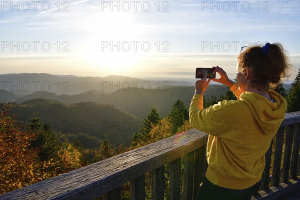 Woman photographing the sunset at Schliffkopf, near Baiersbronn, Freudenstadt district, Black