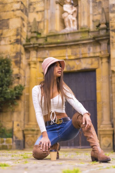 A young Latin woman with a white t-shirt, jeans and a hat enjoying the summer holidays, with a take