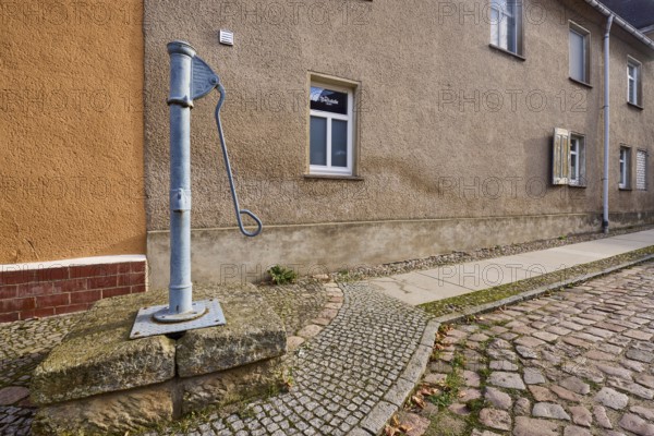 Historic pump, hand pump, pavement, cobblestones, facade with windows, Mühlberg Elbe, Elbe-Elster