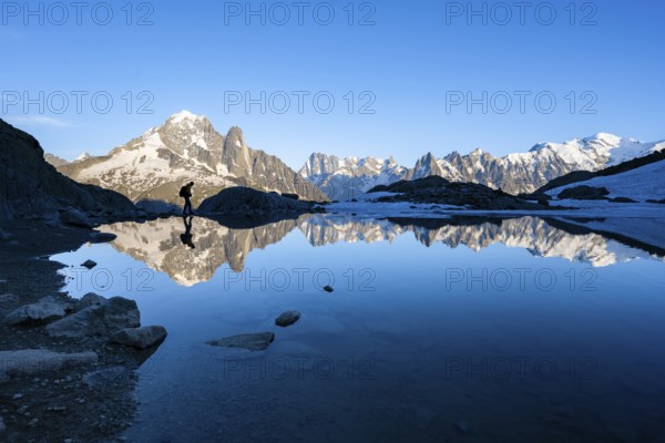 Mountaineer, silhouette in front of mountain landscape in the evening light, water reflection in