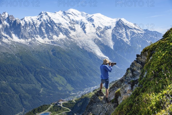 Photographer with zoom lens in mountain landscape, in front of glaciated mountain peak of Mont