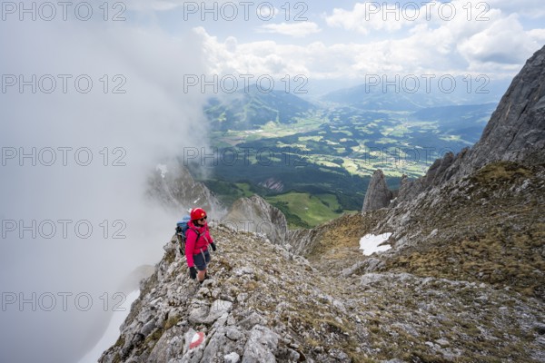 Mountaineer on the rocky ridge, ascent to the Ackerlspitze, clouds moving around the mountains,