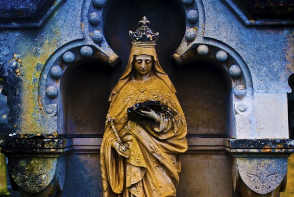 Sculpture of the Virgin Mary reading a book, tombstone in a cemetery, France, color manipulation,