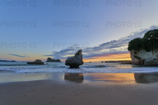 Ocean view with large rocks in the water under a dramatic sunrise sky, Cathedral Cove, Coromandel,