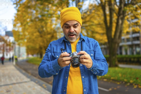 Mature man tourist checking the pictures on the screen of a camera while photographing the city