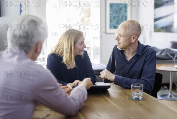 Symbolic photo on the subject of counselling. A young woman and a young man sit together at a table