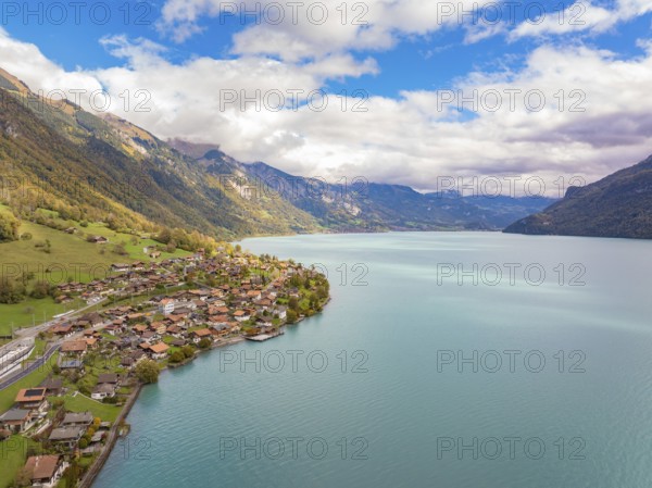 Village on the shore of a large lake, surrounded by mountains and clouds, panoramic style, Lake