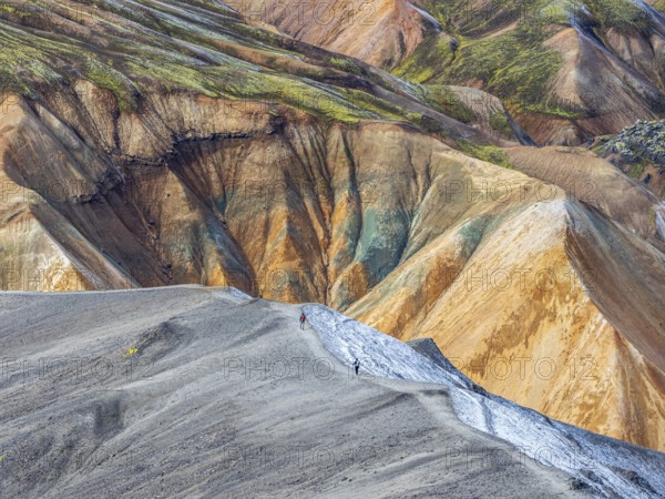Hikers decending the slopes of Mt. Blahnukur, colorful rhyolite mountains, lava field,