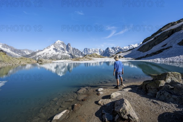 Mountaineer in front of mountain landscape with mountain lake, tourist at Lac Blanc with water