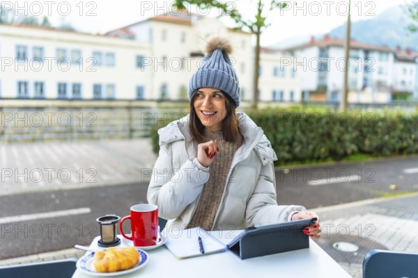 Creative caucasian beauty woman with warm clothes using digital tablet while drinking tea sitting