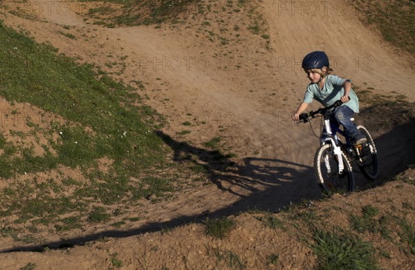 Little boy, 5 years, blond, rides with bicycle, crash helmet, cross, cross track, playground,