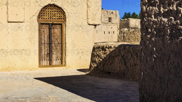 Decorated round arch entrance door in the largest preserved mud town in Oman, Al Bilaad, Al Bilaad