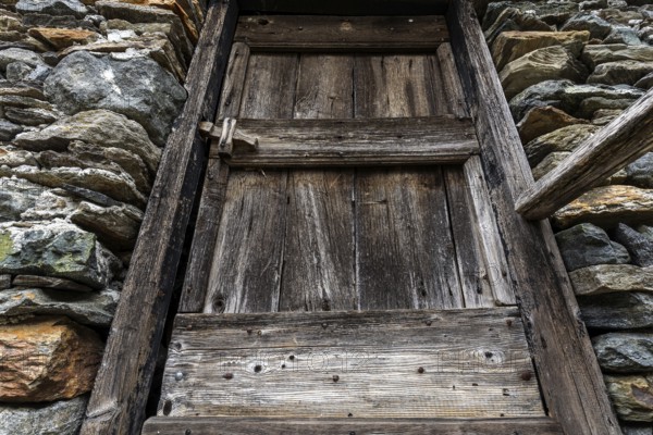 Old wooden door of a typical Ticino stone house in the mountain village of Bordei, Centovalli,