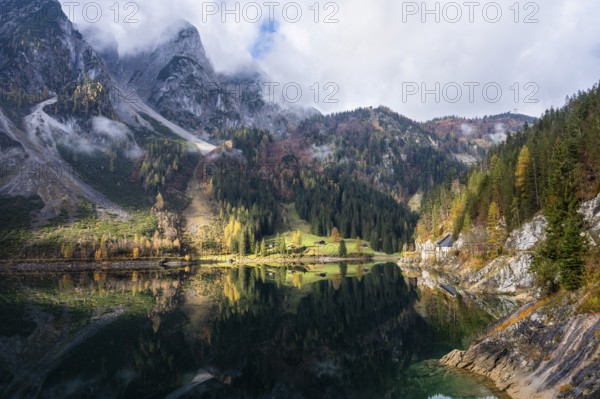 The Vordere Gosausee in autumn. The Gosaukamm on the left. Clouds and sun. Reflection. Vorderer