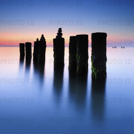 Stone pyramids on old groynes with algae in the water on the beach of the Baltic Sea, long exposure