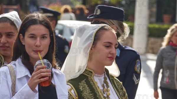 Young woman, one in traditional traditional costume, the other with a drink in her hand, on the