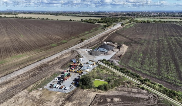 Construction vehicles are parked at an access road under construction to the High Tech Park at the