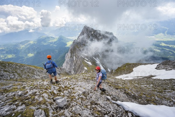 Mountaineer with helmet on a narrow hiking trail, ascent to the Ackerlspitze, clouds moving around
