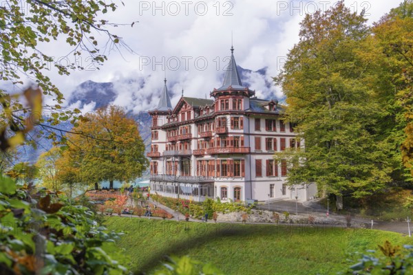 Large hotel against a mountain backdrop in autumnal surroundings with dramatic clouds, Grandhotel