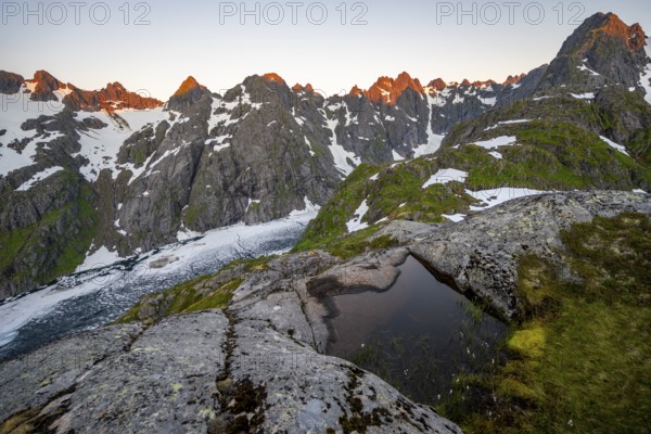 Rocky mountain peaks and Trollfjordvatnet with snow, small pond in moorland at Trollfjord Hytta,
