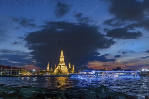 Wat Arun, Temple of Dawn at sunset with dark clouds. Boats on the Chao Phraya river. Tourist