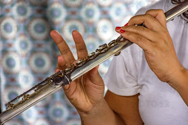 Detail of the hands of a woman playing the transverse flute during a musical performance Belo