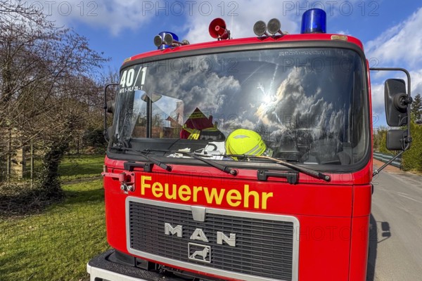 Front of red fire engine MAN truck with yellow lettering fire brigade above siren megaphone blue
