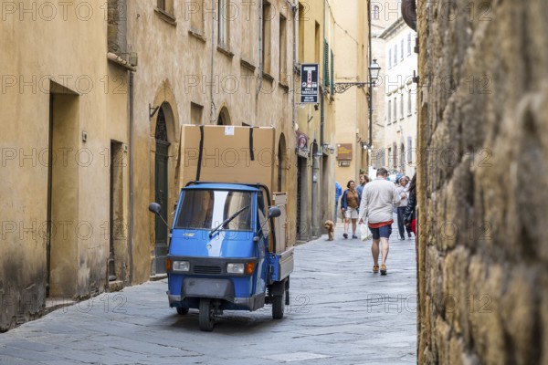 Three-wheeled Piaggio Ape van packed full in an alleyway in the historic centre of Volterra,