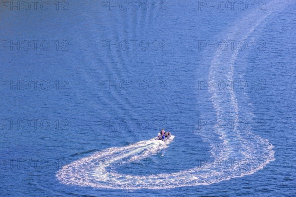 Inflatable boat with people turning on the sea and making wake pattern on the water surface, Crozon