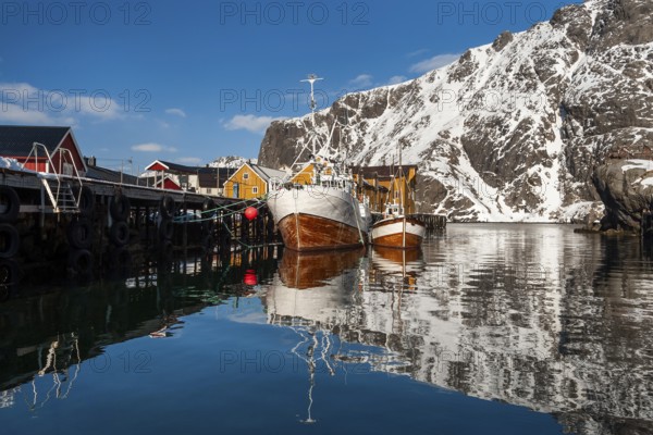 Fishing boats, fishing village with yellow houses in front of snowy mountains, Nusfjord,