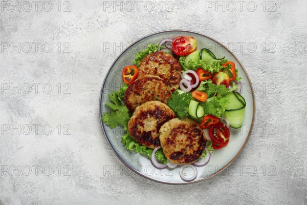 Fried chicken cutlets, minced chicken, with vegetables, on gray, with vegetable salad, top view,