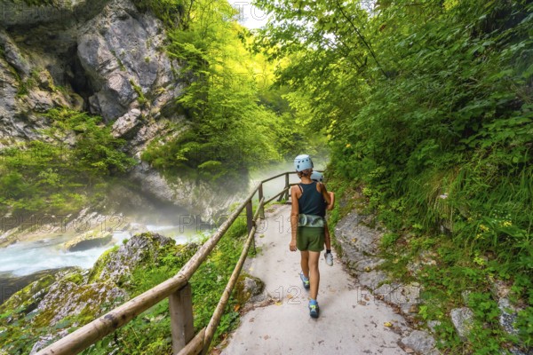 Tourists walking on a pathway along the radovna river in vintgar gorge, enjoying the scenic beauty