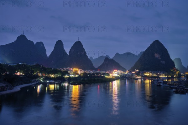 View of Yangshuo town illuminated in the evening with dramatic karst mountain landscape in