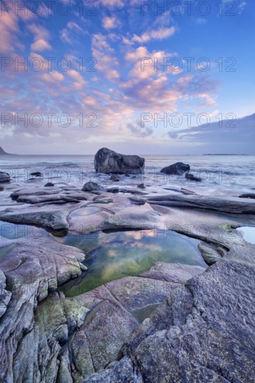 Rocks on beach of fjord of Norwegian sea in winteron sunset. Utakliev beach, Lofoten islands,