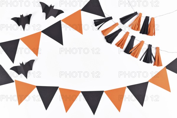 Halloween background with garlands and paper bats in traditional colors orange and black on white