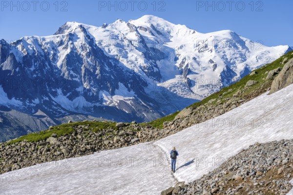 Mountaineer crossing a snowfield, view of spectacular glaciated peaks of Mont Blanc, Mont Blanc