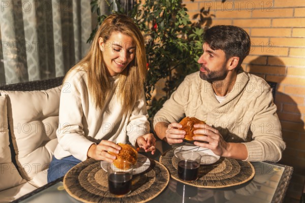 Happy couple enjoying burgers and wine on a cozy terrace, creating a romantic and intimate