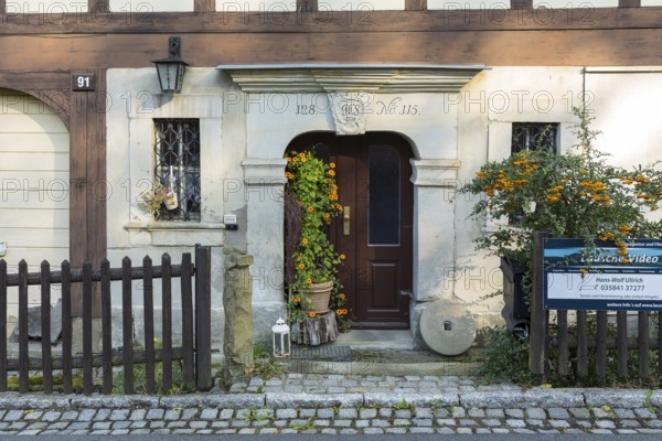 Historic door frame and loving decoration with millstone and flowers in front of a typical