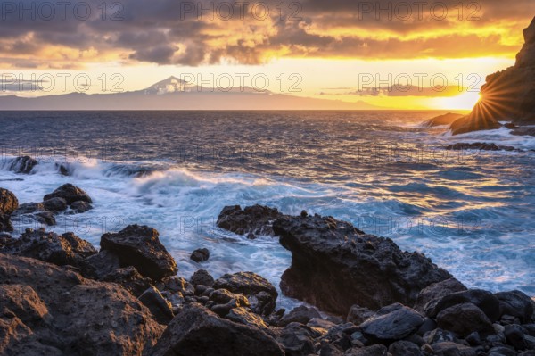 Sunrise on the beach at San Marcos. Rocks, sea and the sun. Tenerife and the Teide in the