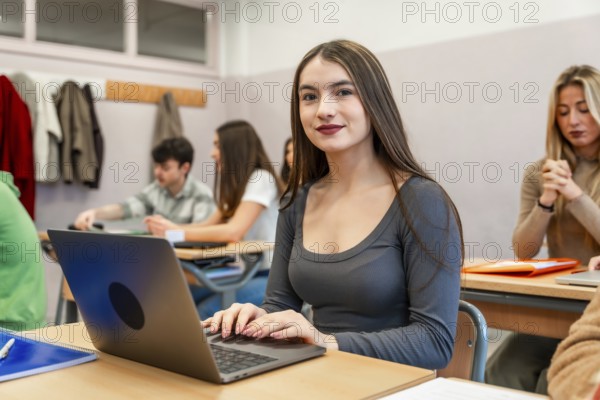 Young woman using laptop in university classroom, participating in an engaging lesson with her